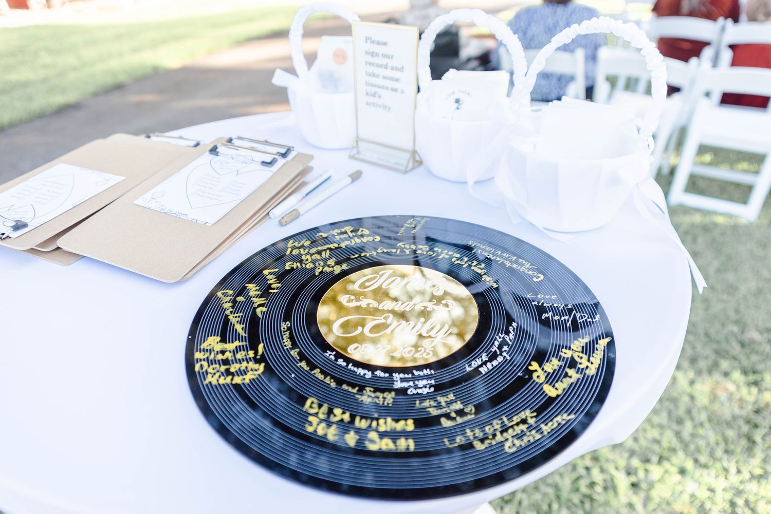A record is being used as a guest book for a wedding and is placed near baskets and clipboards.