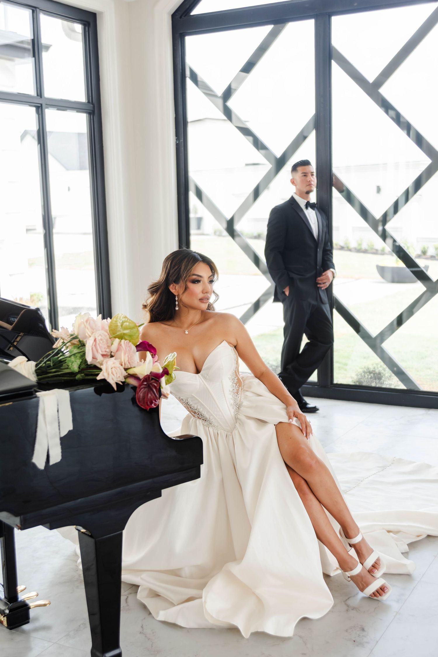 A bride sits while the groom stands looking into the distance