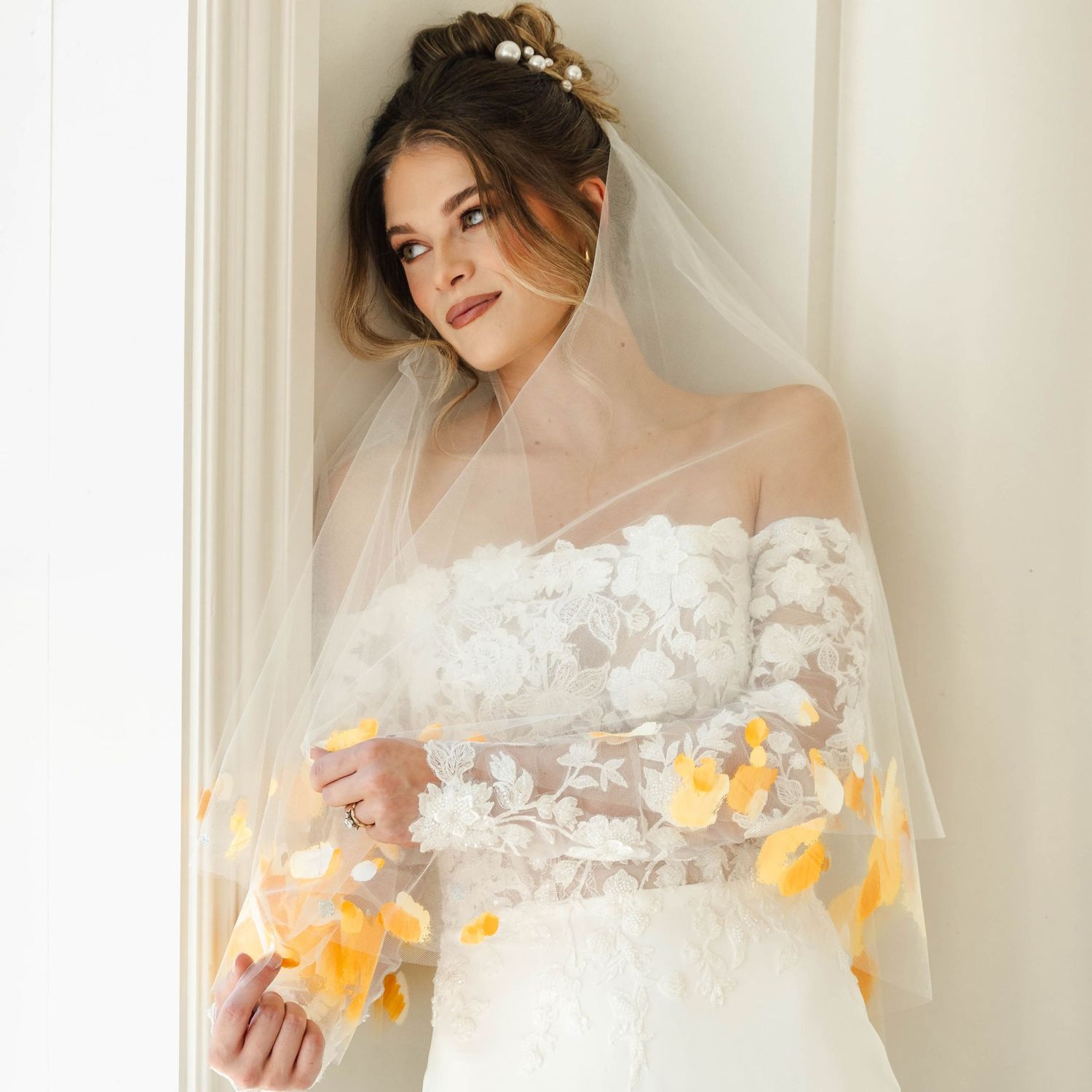 Bride looking out a window softly touching her veil