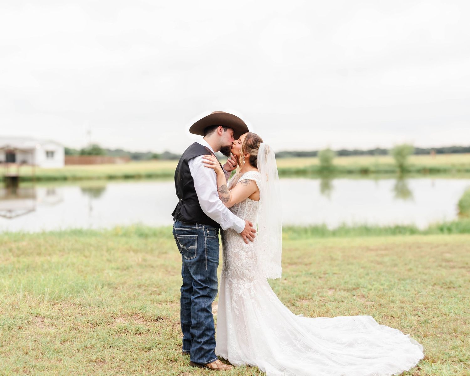 A couple kisses in front of a pond