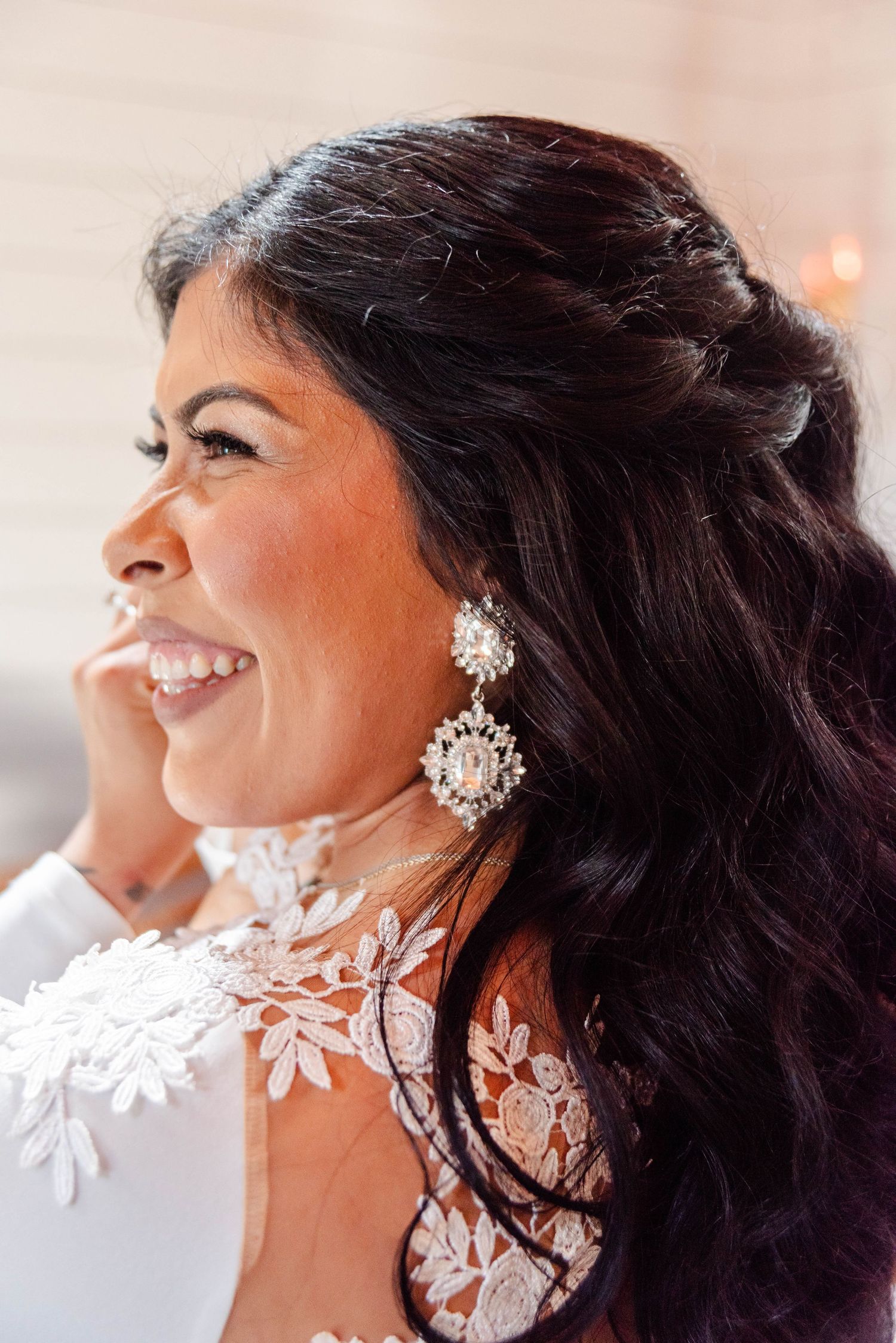 a bride smiles as she fixes her earring