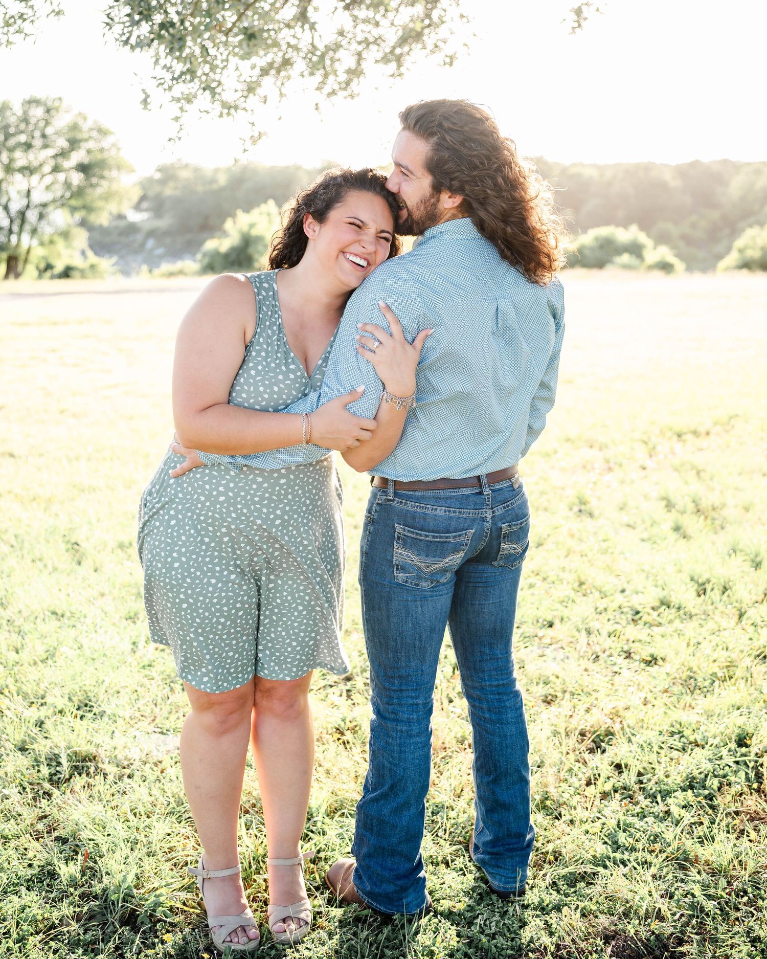 a woman laughs while her fiance holds her