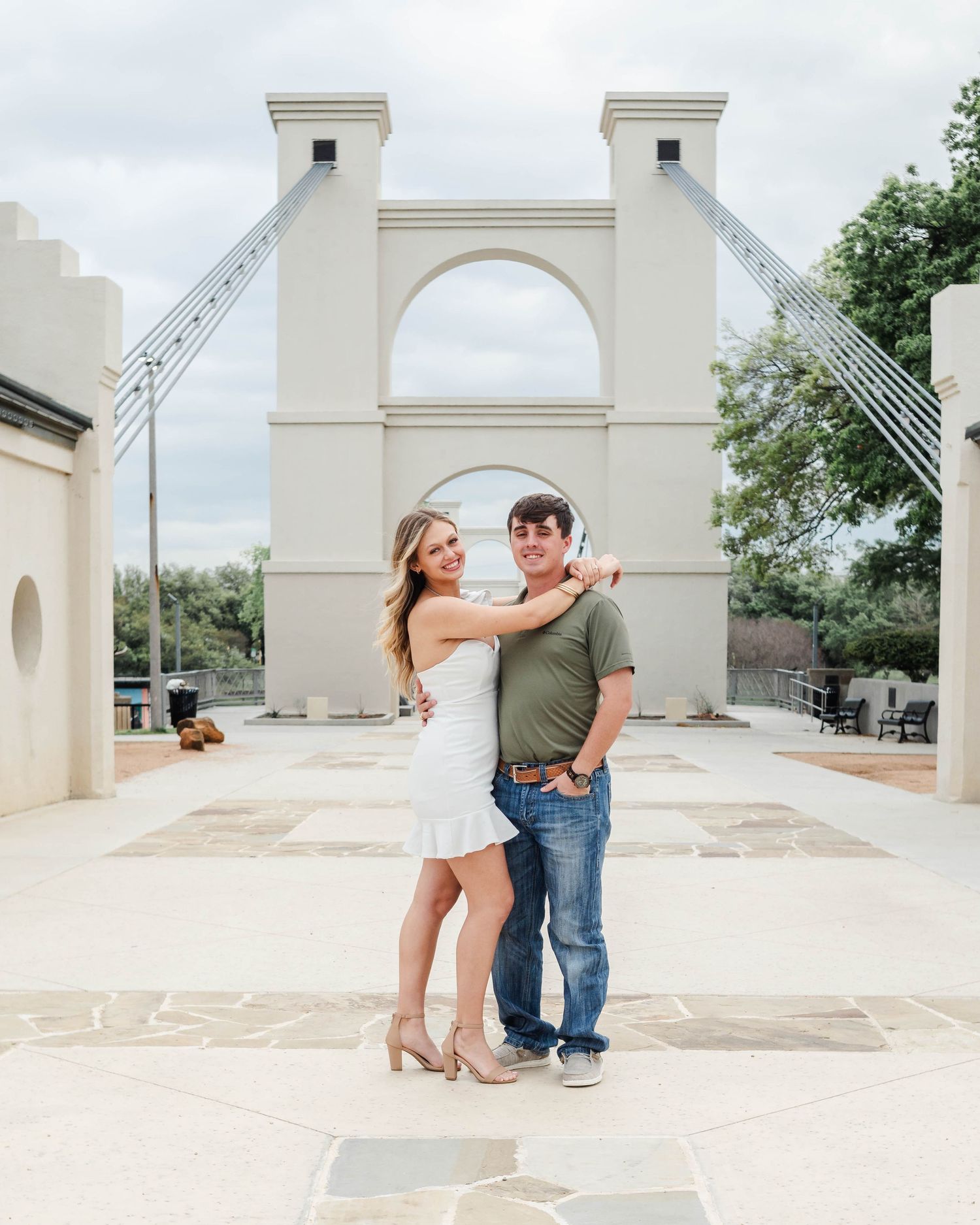 Couple standing at the Waco Suspension Bridge in Waco, Texas