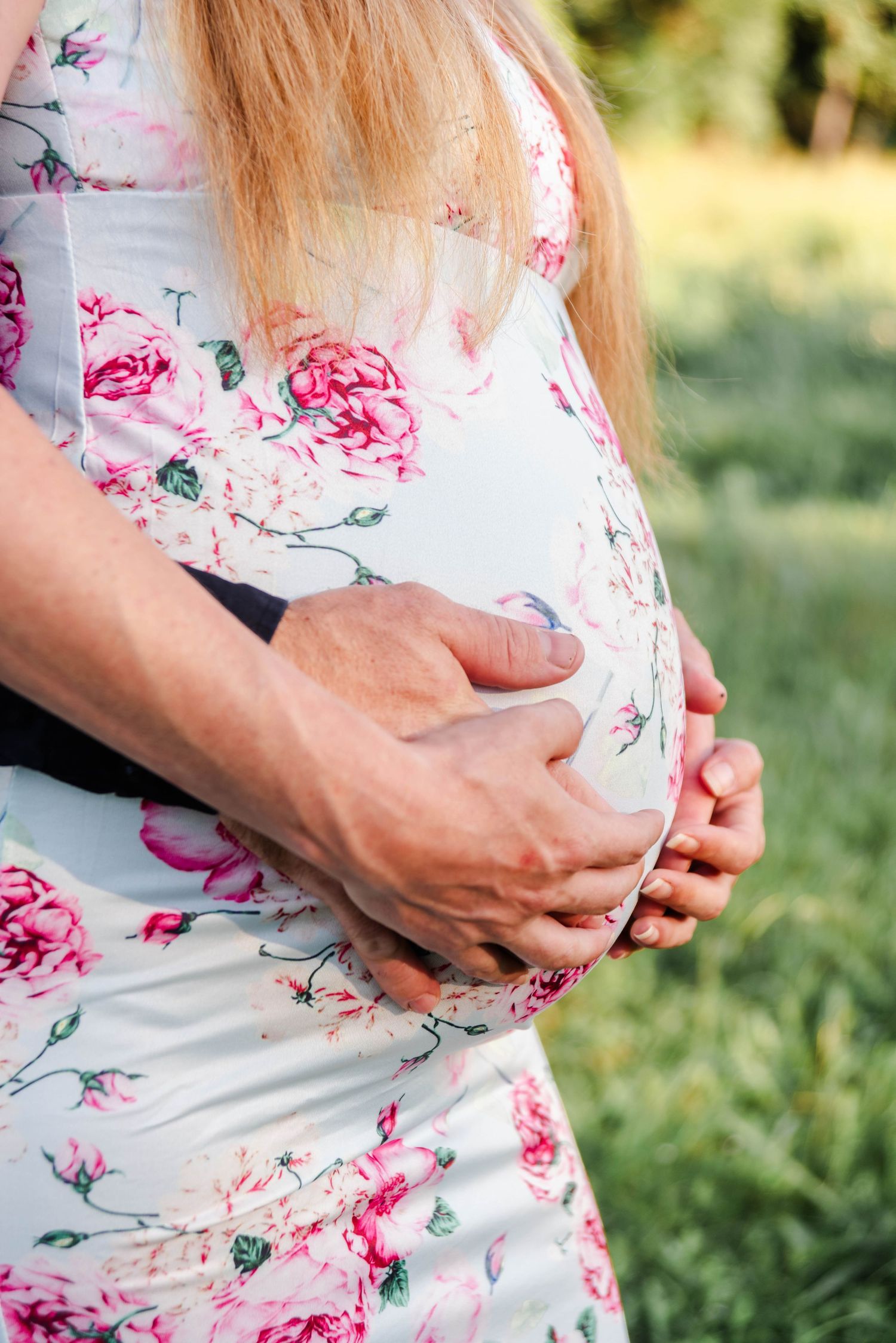 a couple holds their hands around the woman's baby belly