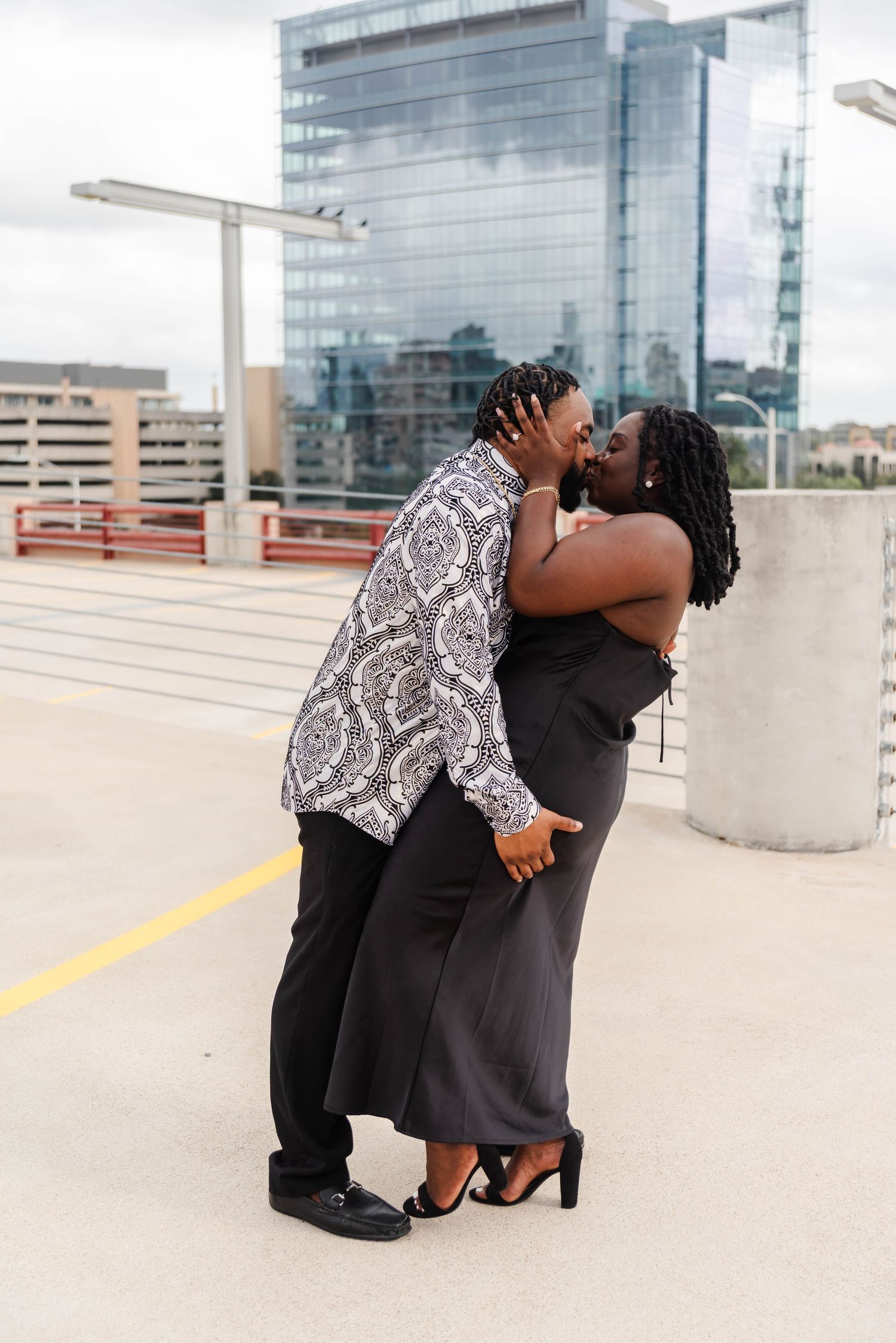 a couple is kissing on a rooftop with a downtown view