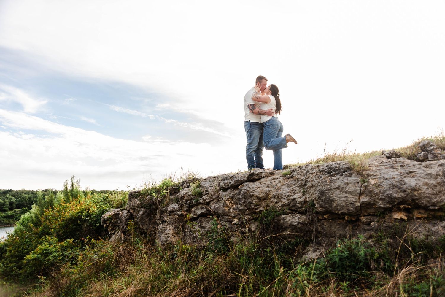 a couple kisses while standing on a rocky hillside