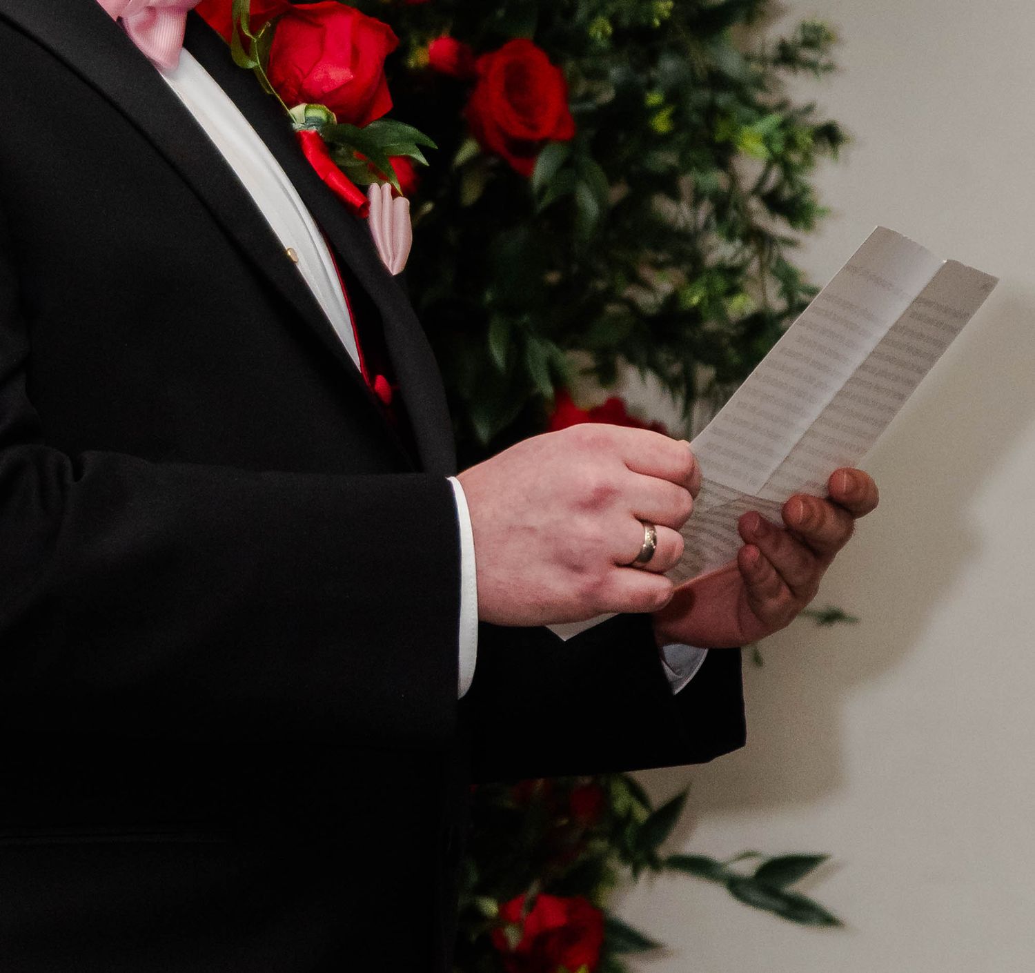 A man holding wedding vows in his tuxedo at the alter