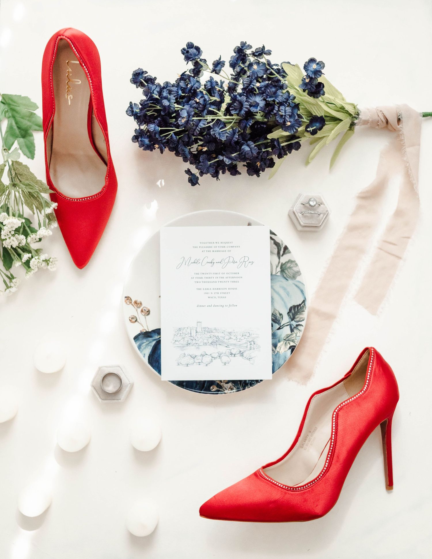 A flat lay of an Invitation to a Wedding with red heels