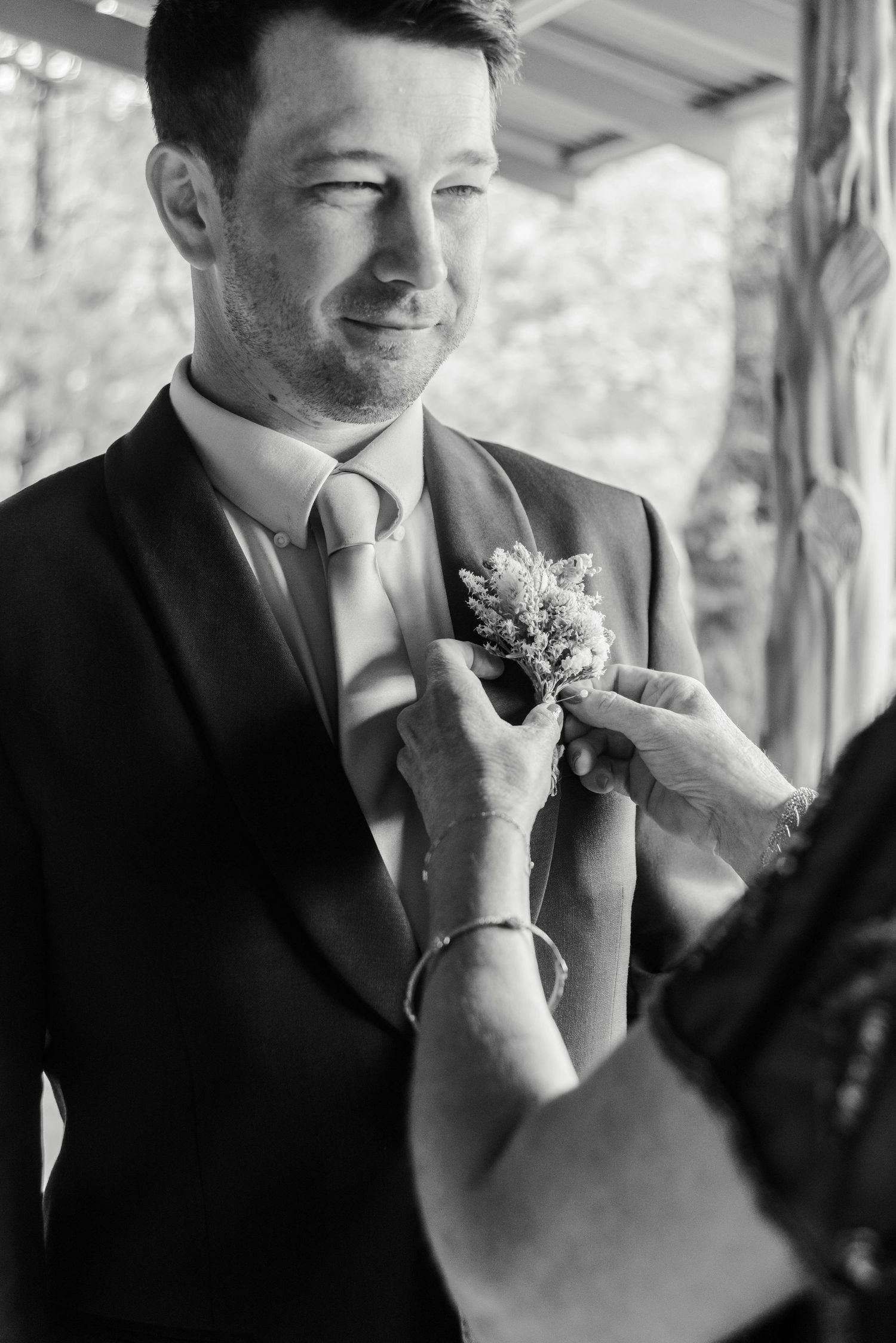 a mother pins a grooms boutonniere