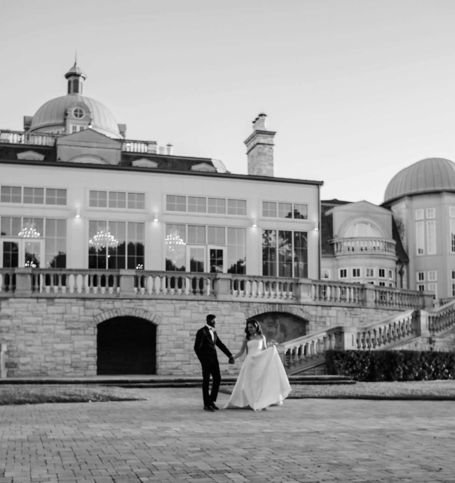 A couple strolls through the back patio of a large french inspired venue