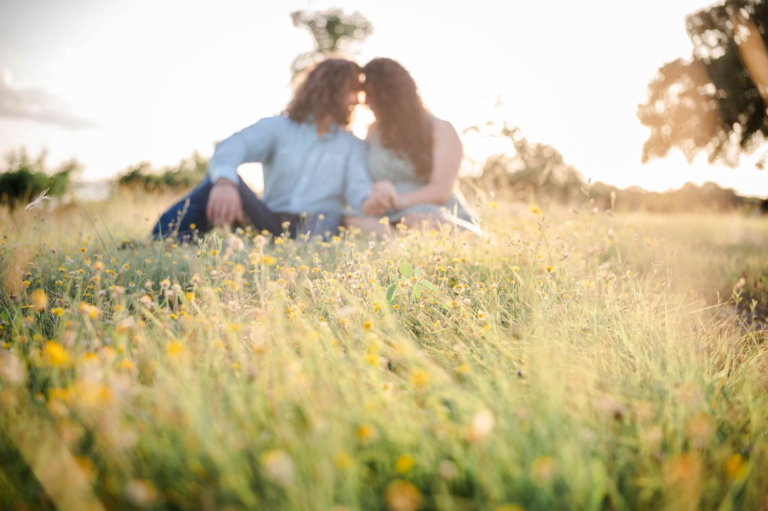 a couple sits together facing each other while the sun sets
