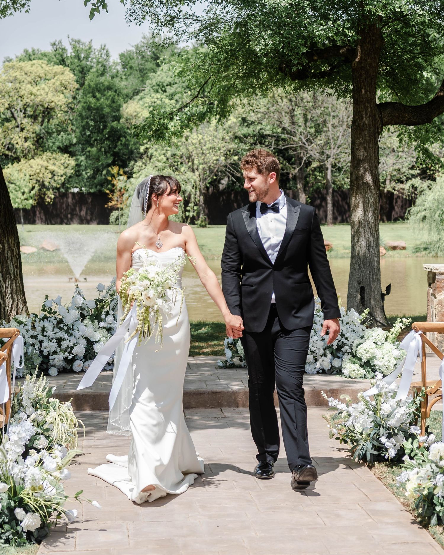 A couple walking down the aisle holding hands and smiling at each other