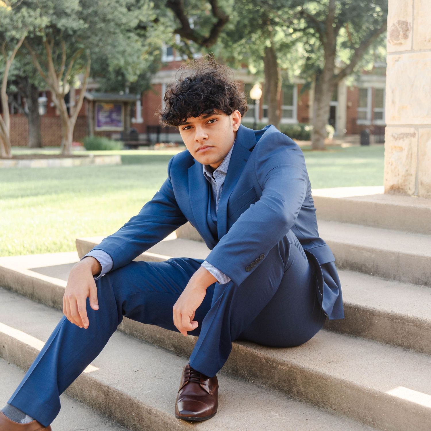 a grad sitting on steps at a college