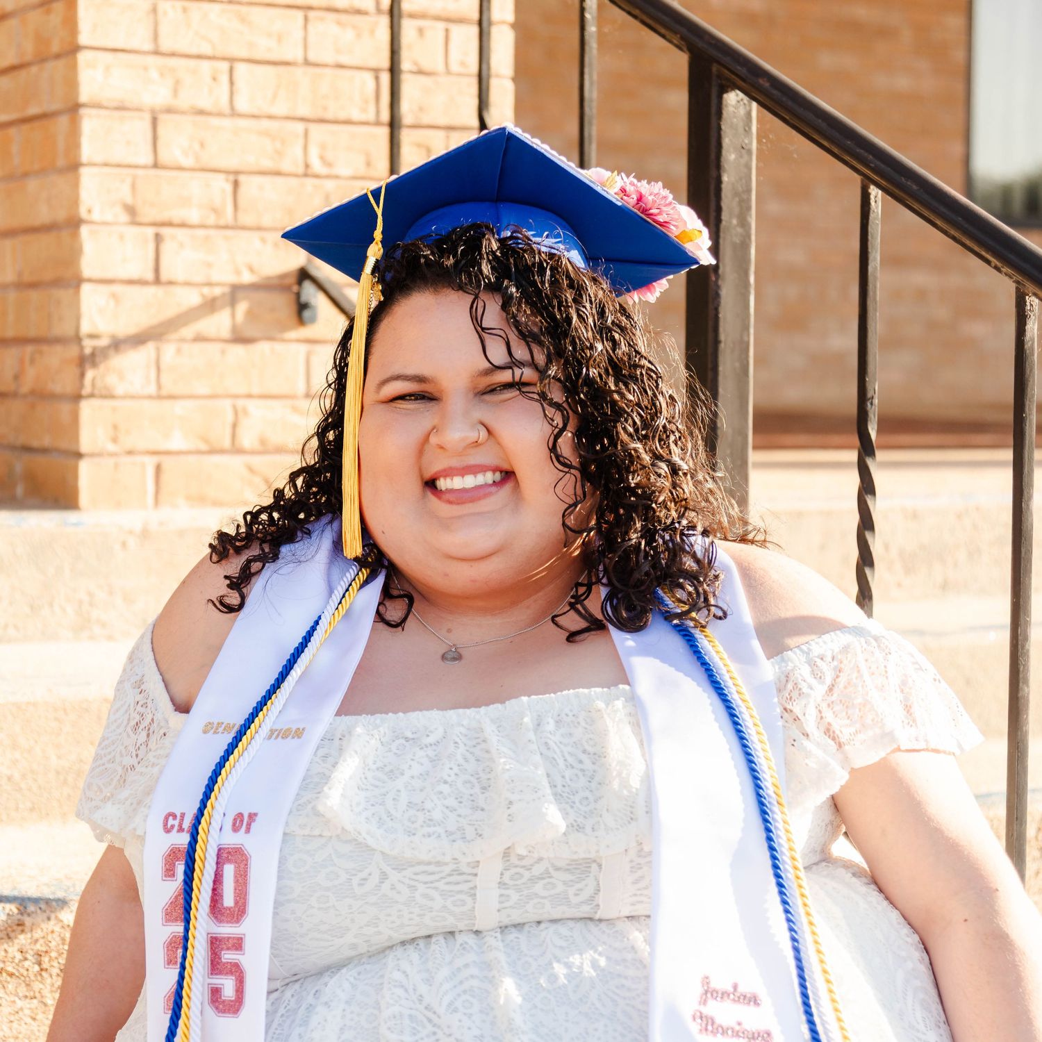 A female is wearing a graduation cap and smiling