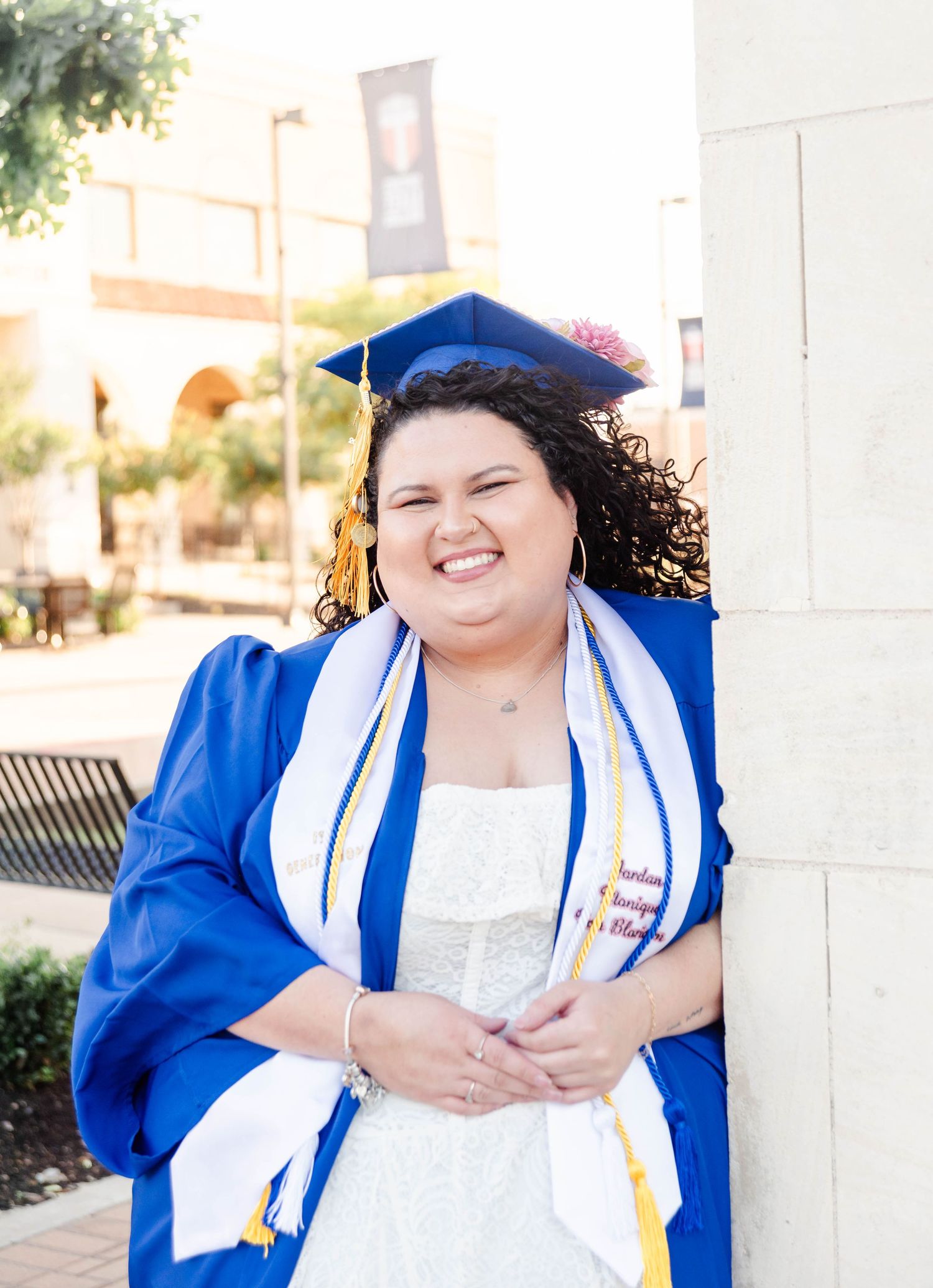 a girl leaning on a wall with a cap and gown on for graduation