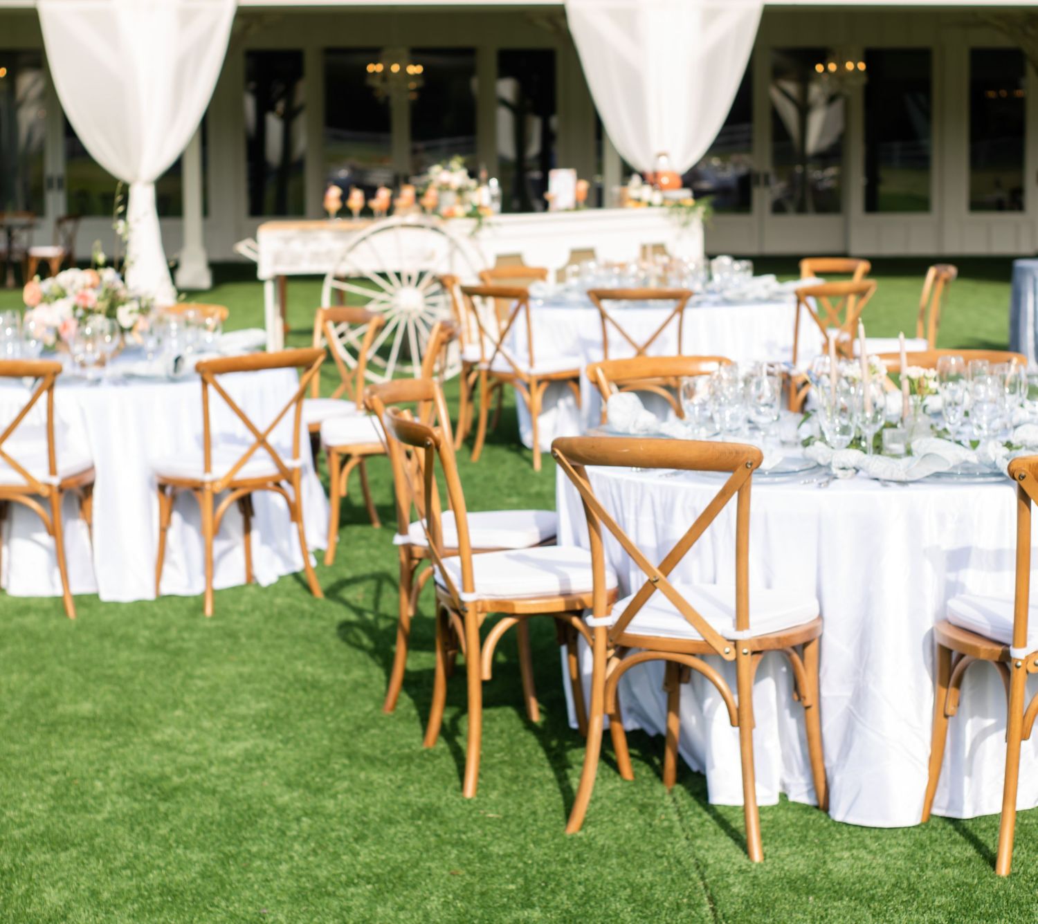 tables set for an event with a bar cart in the back. the tables are done in white and floral