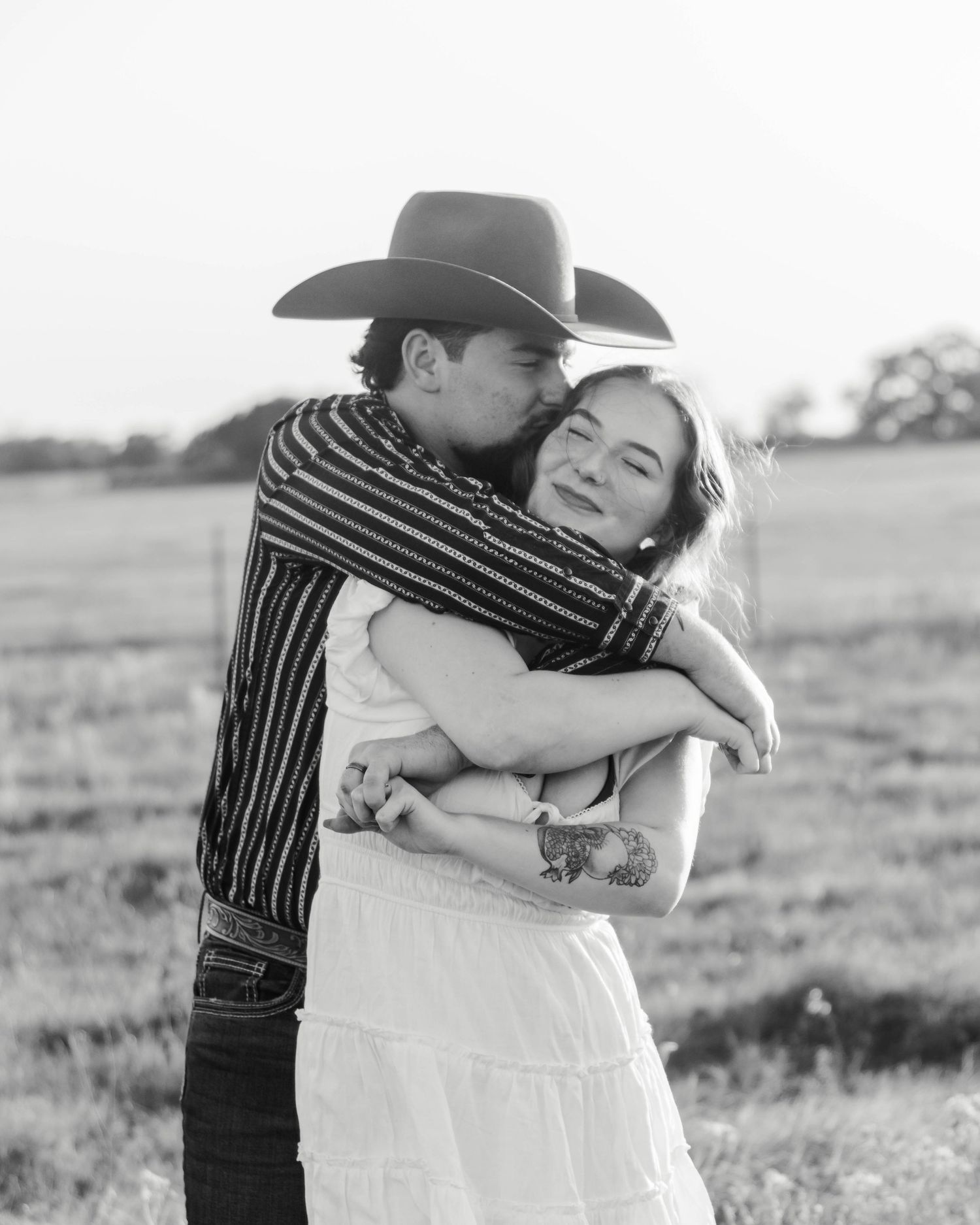 man is kissing a woman on her cheek and they have their arms wrapped around each other.
