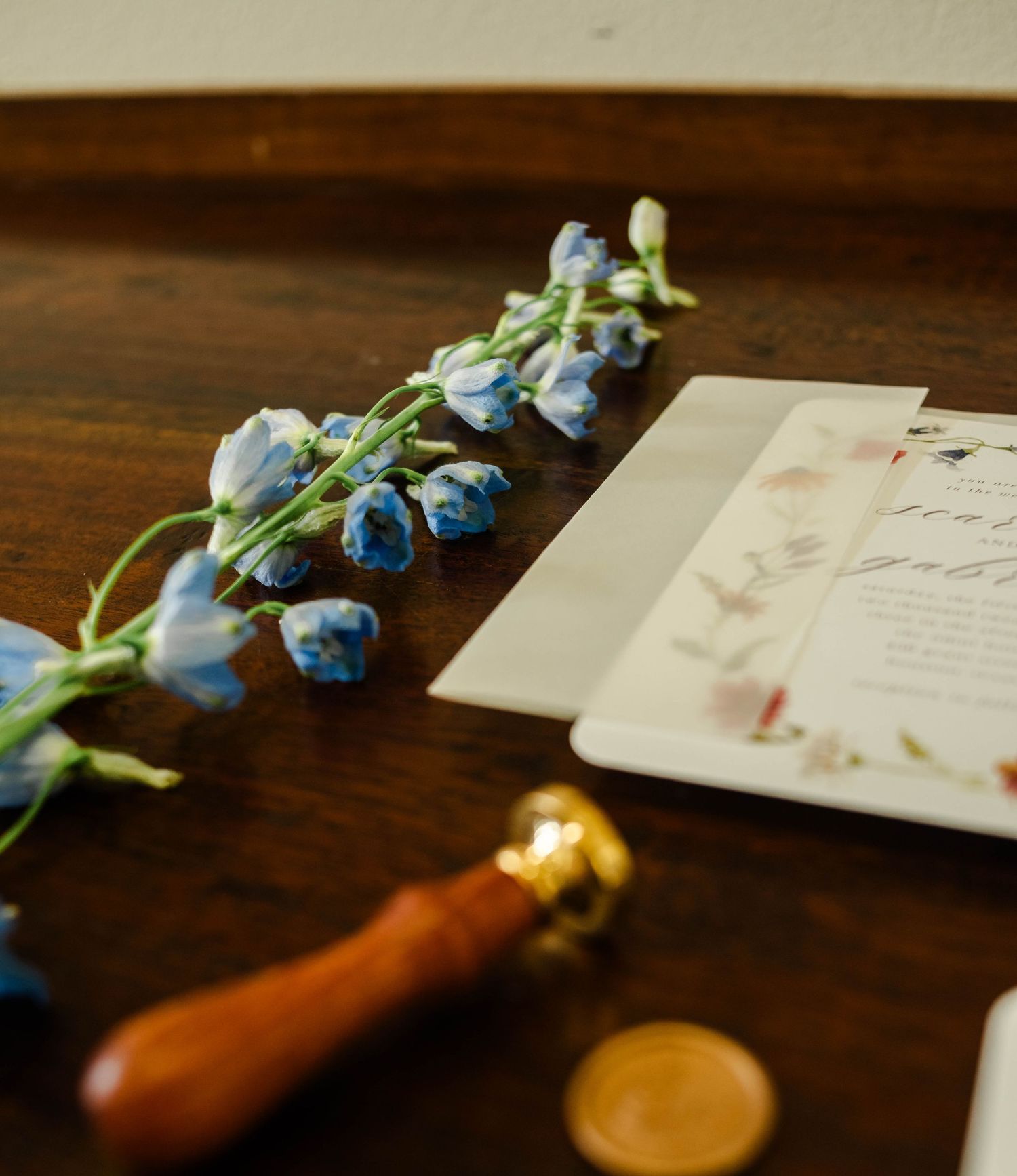 Blue flowers set next to a wedding invitation and stamp