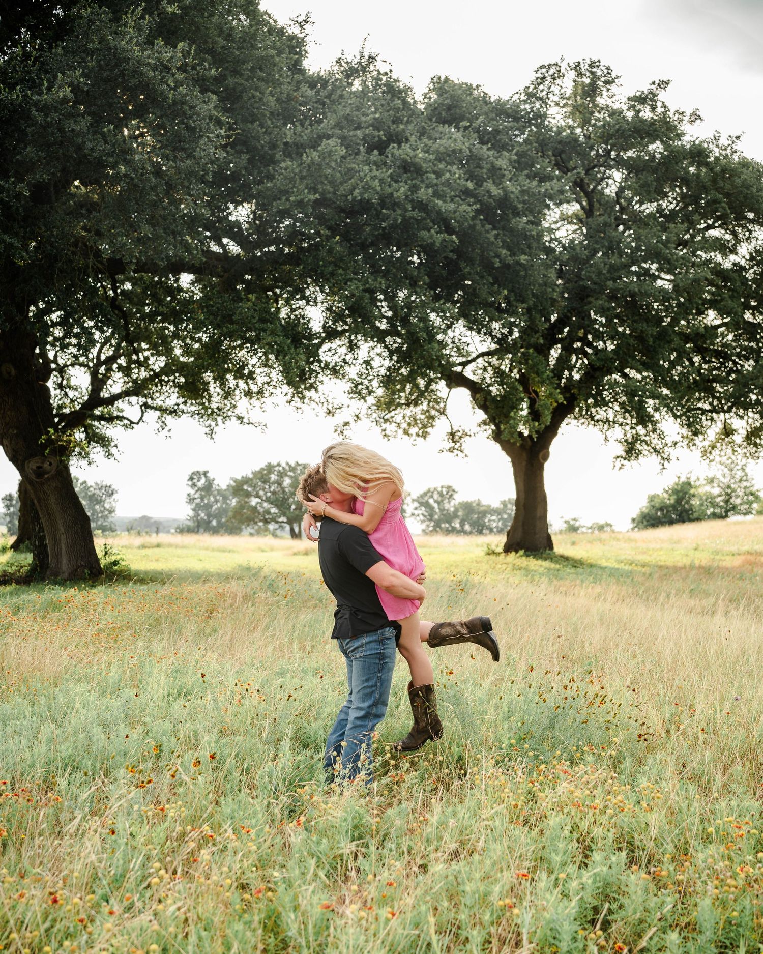 a man lifts a woman in the air and she kisses him