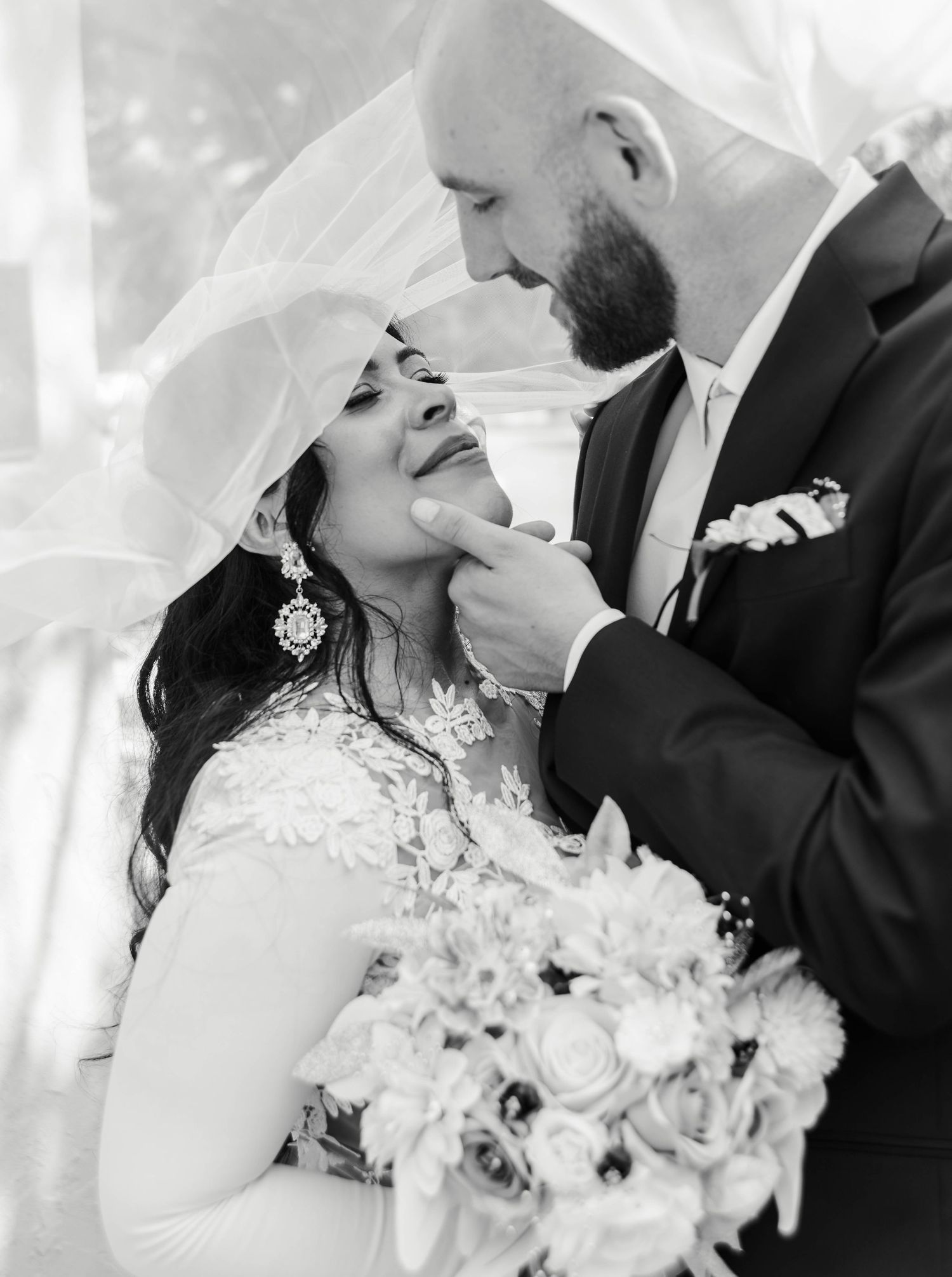 a groom holds his bride's face gently