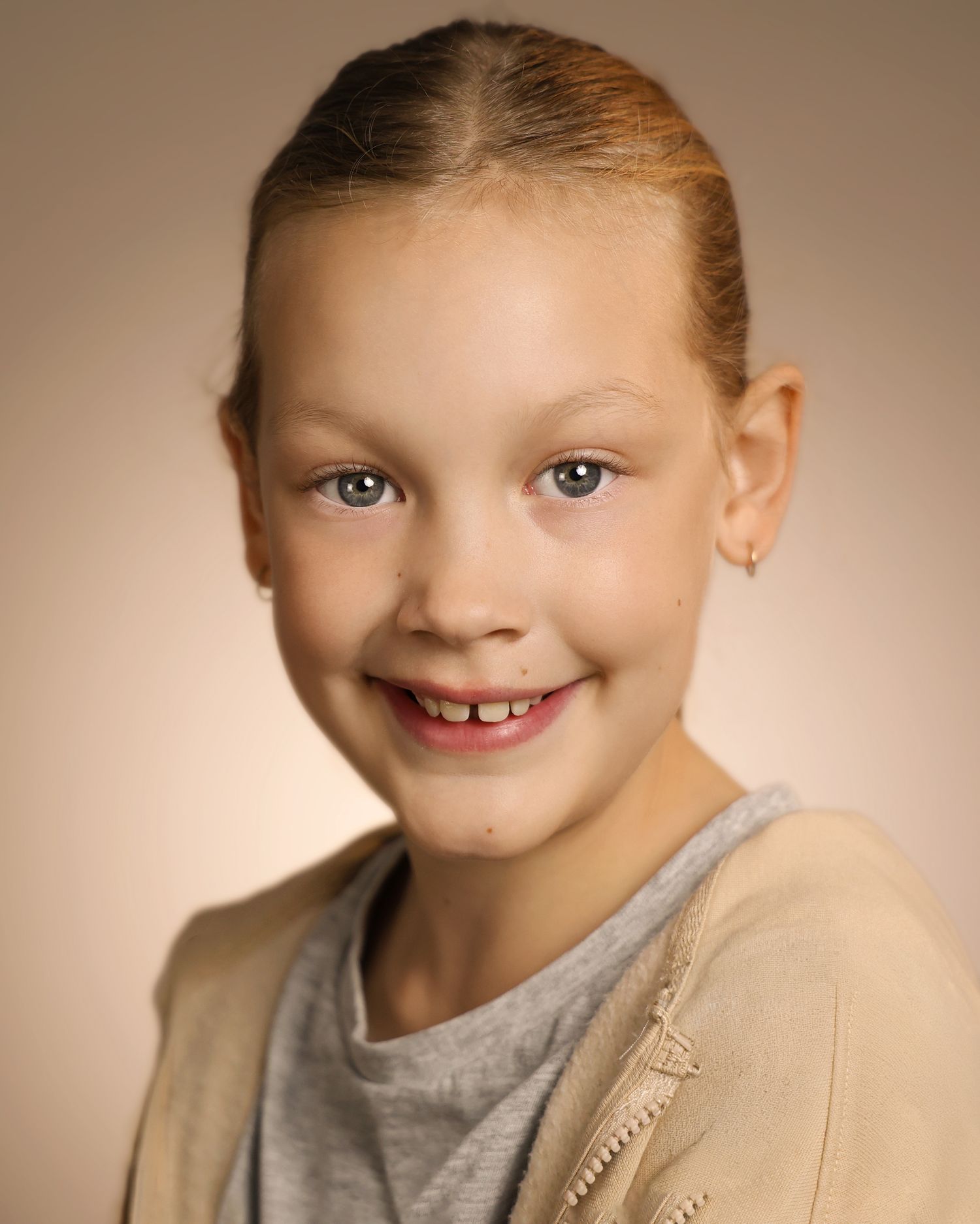 Young girl with blonde hair pulled back, smiling warmly in a professional school portrait photo.
