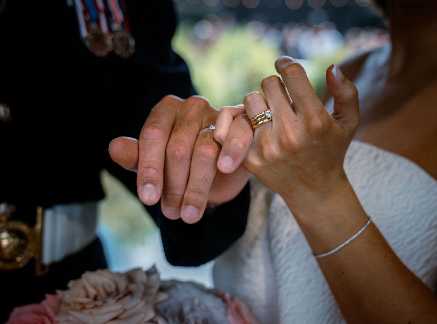 Close-up of newlyweds holding hands, bride wearing a gold diamond ring on her wedding day.