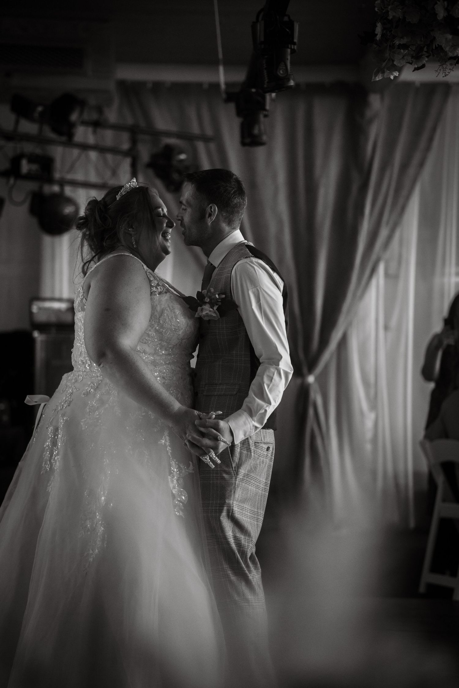 Elegant black and white photo of bride and groom sharing a tender first dance at their wedding reception.