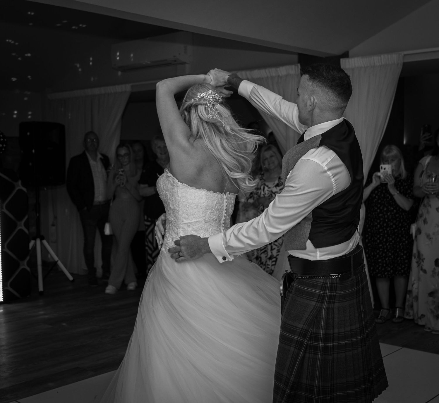 Black and white photo of bride and groom sharing first dance at wedding reception.