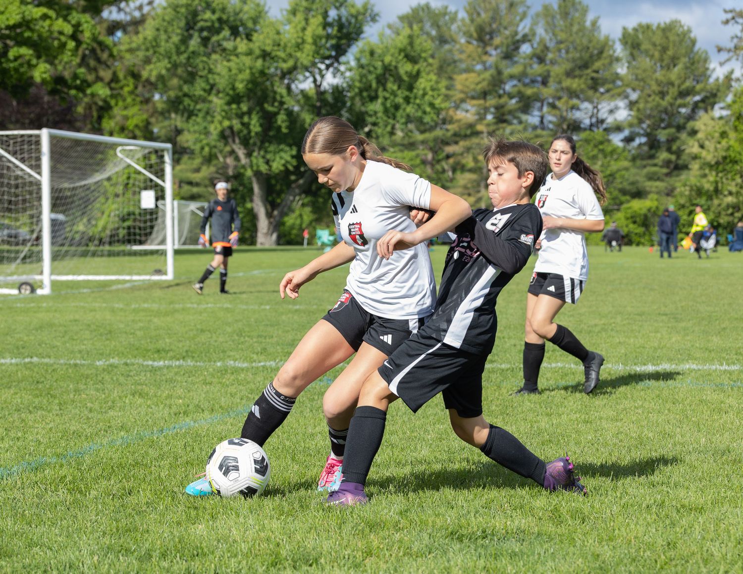 action sports soccer game female player wearing white uniform going for the ball elbowing a male player in black