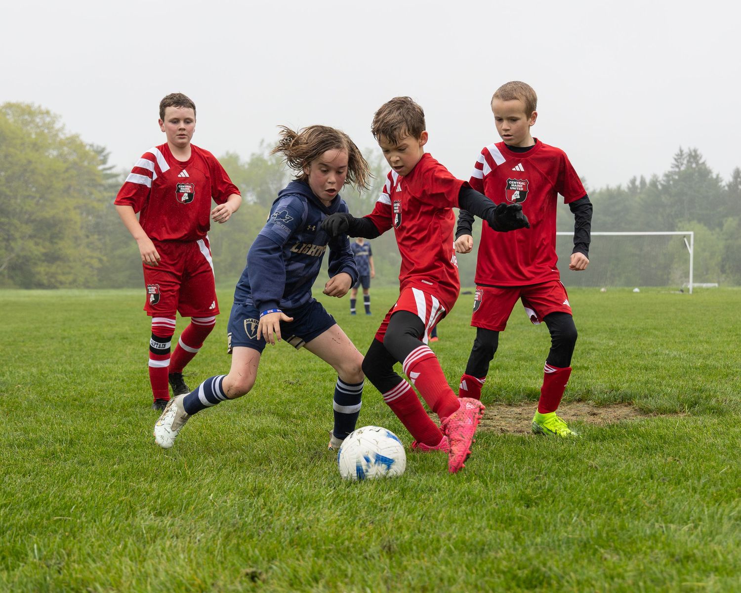 action sports game soccer group of young male players keeping the ball in game raining foggy red uniforms