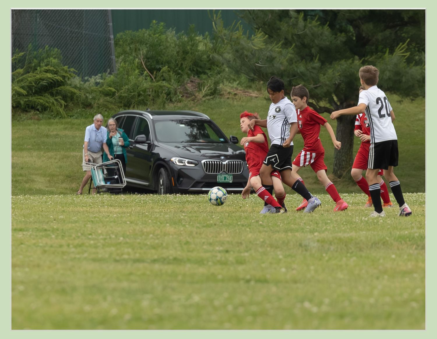 action sports game soccer young male player in red uniform falling from push elderly couple watching and pointing at scene