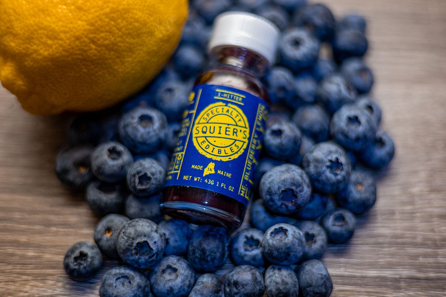 brand product image of medicinal use liquid on a pile of blueberries and a lemon on a wooden surface