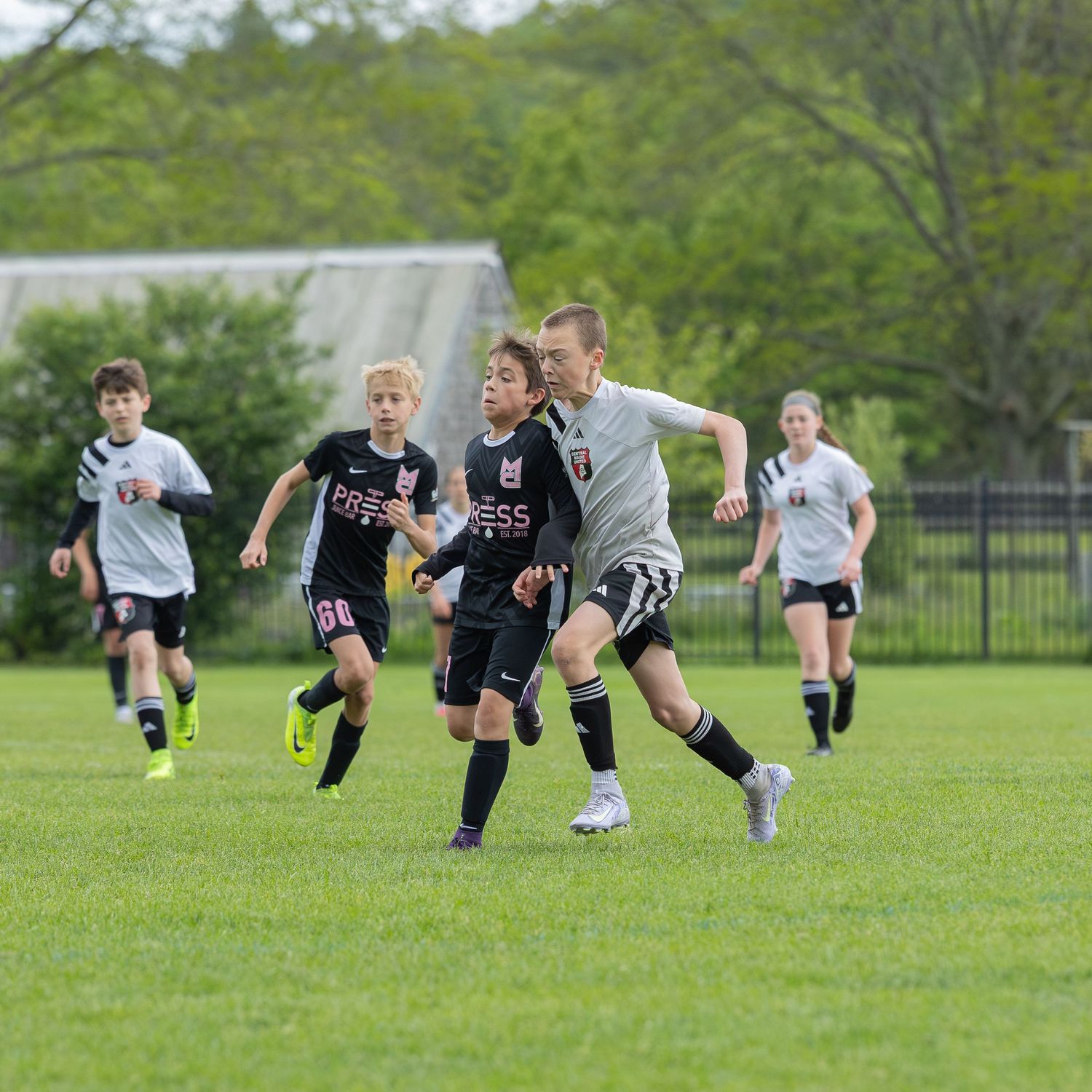 action sports soccer game male teens running for the ball wearing black and white uniforms