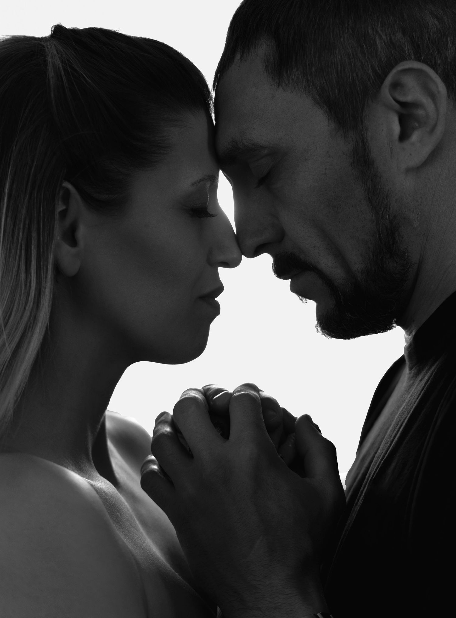 black and white image of a couple pressing their foreheads together holding hands