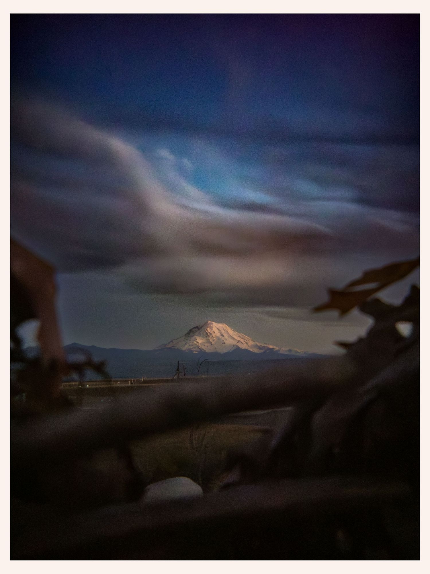 landscape portrait of Mount Rainier Washington state dark clouds with sunlight coming through clouds lighting the mountain