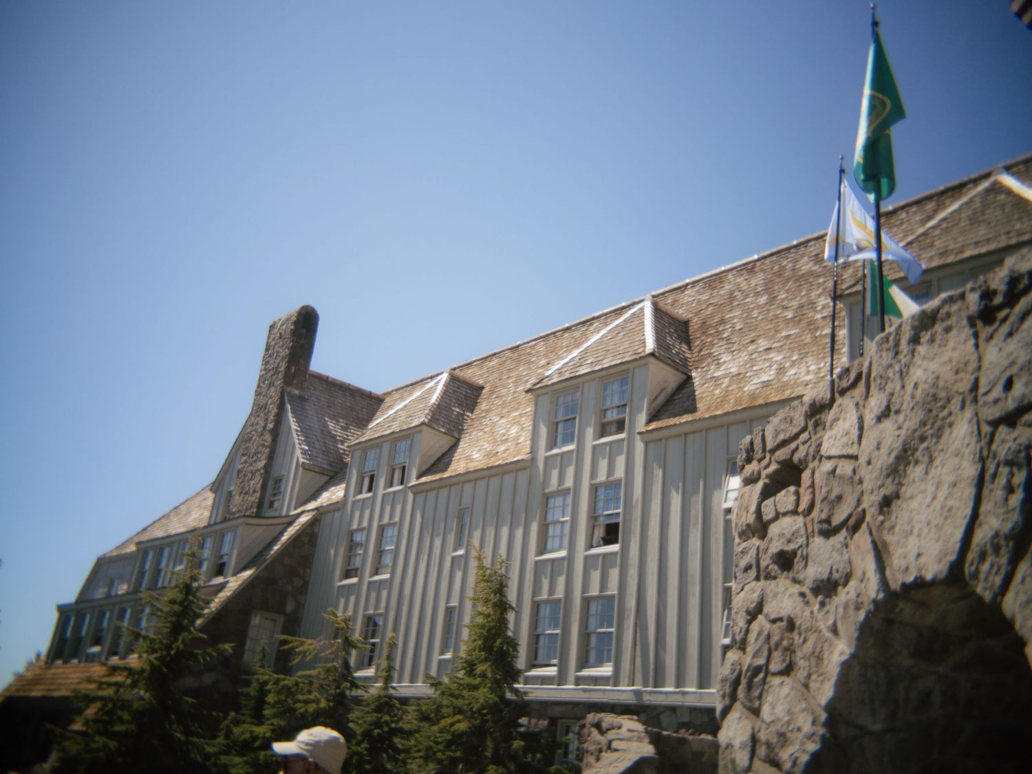 Historic stone and wood lodge building with green flag against clear blue sky.