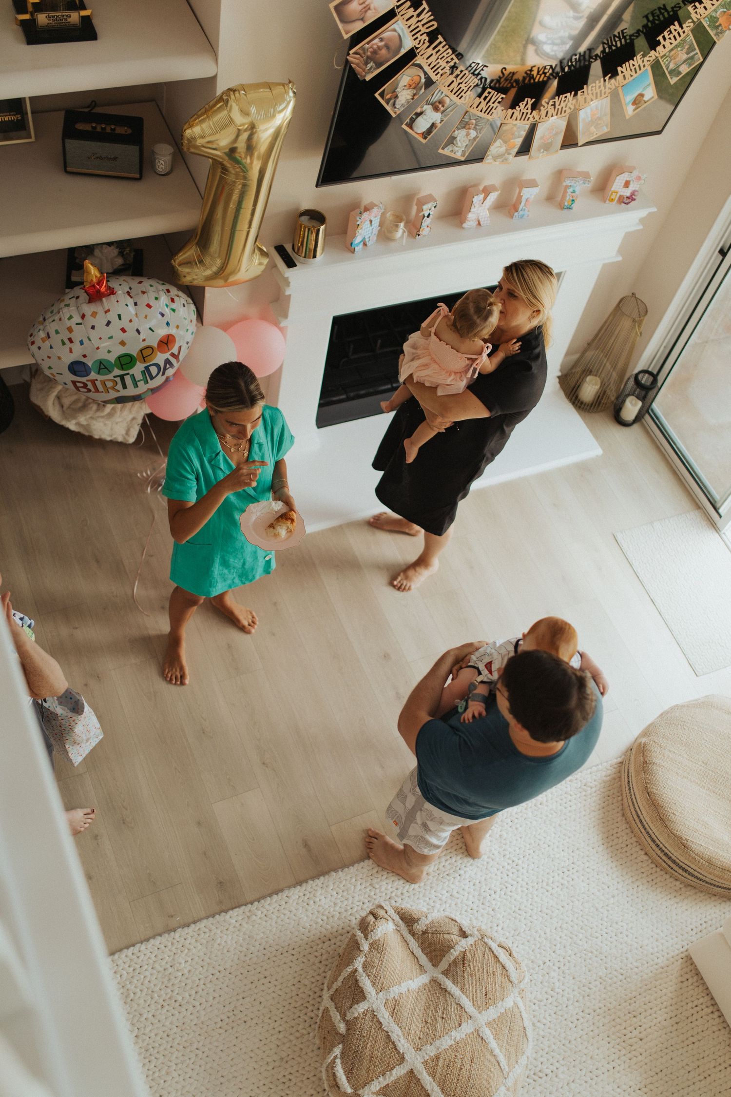 Family gathers indoors at baby first birthday party celebration.
