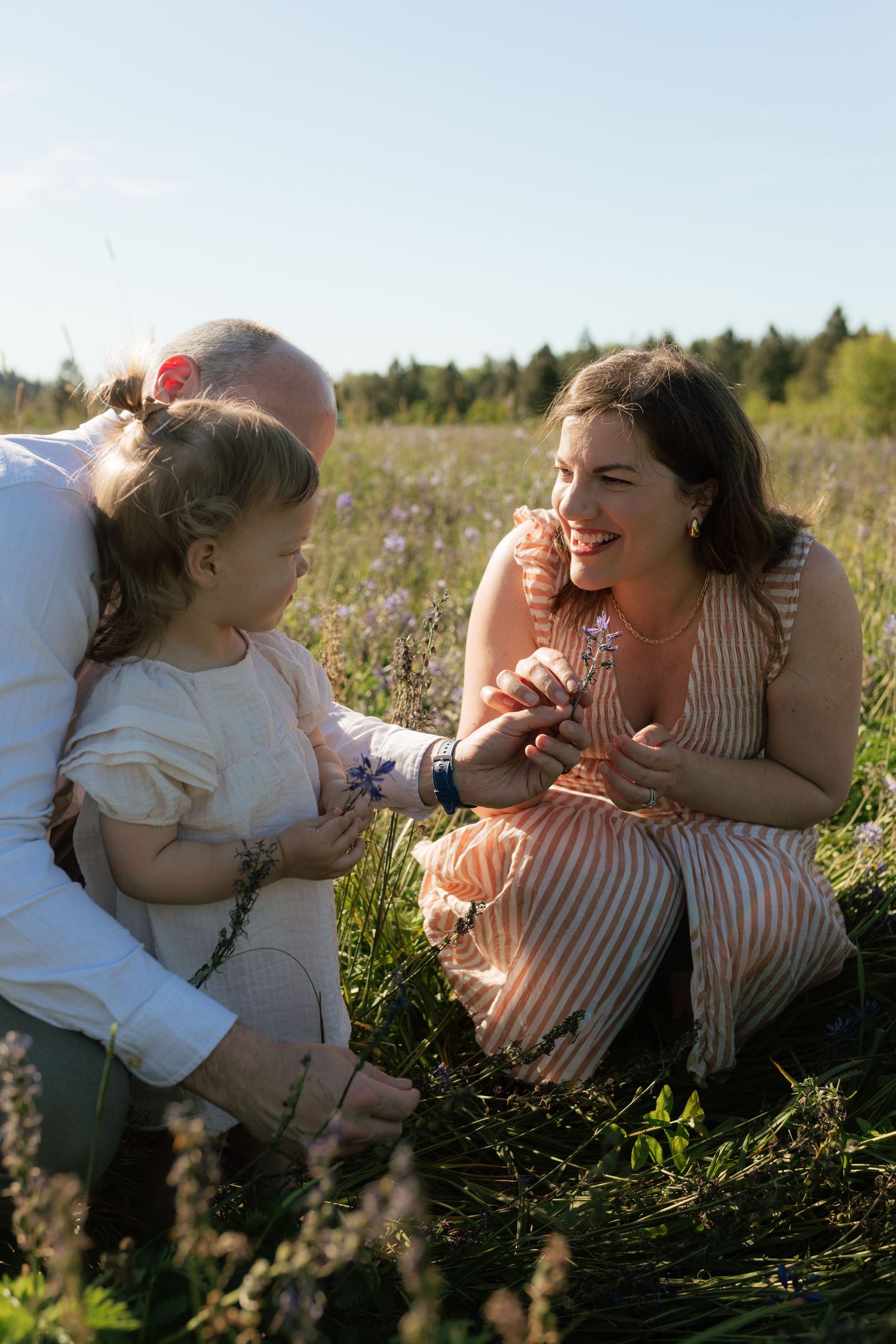 Happy family with young daughter sharing a moment in a sunny wildflower meadow. Oregon family photographer.