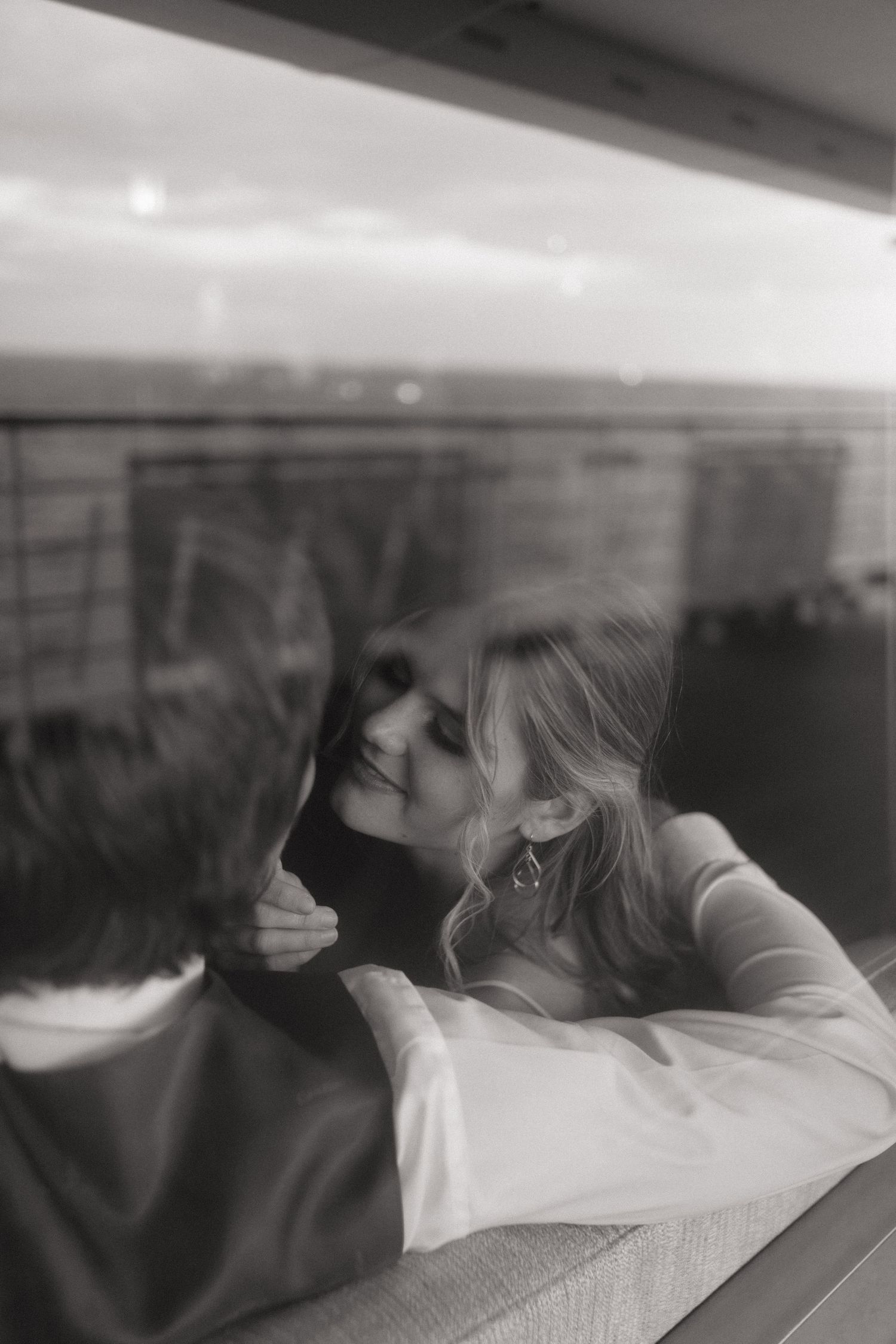 Black and white photo of a couple sharing a romantic kiss near a window on a cruise ship.