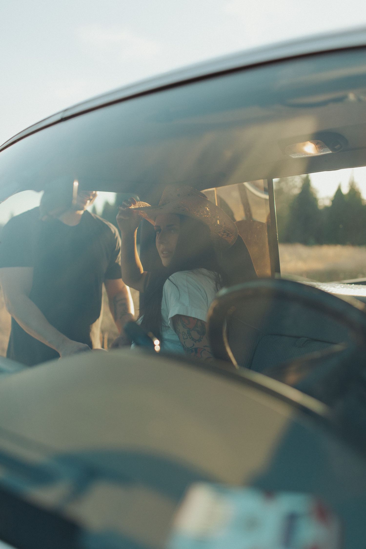 A couple leans together inside a vintage pickup truck cab, bathed in warm golden sunlight through the windshield.