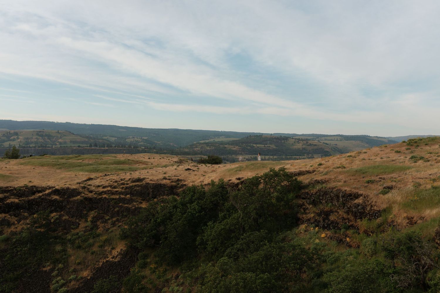 Vast moorland landscape with rolling hills, rocky terrain, and sparse vegetation under a cloudy sky.