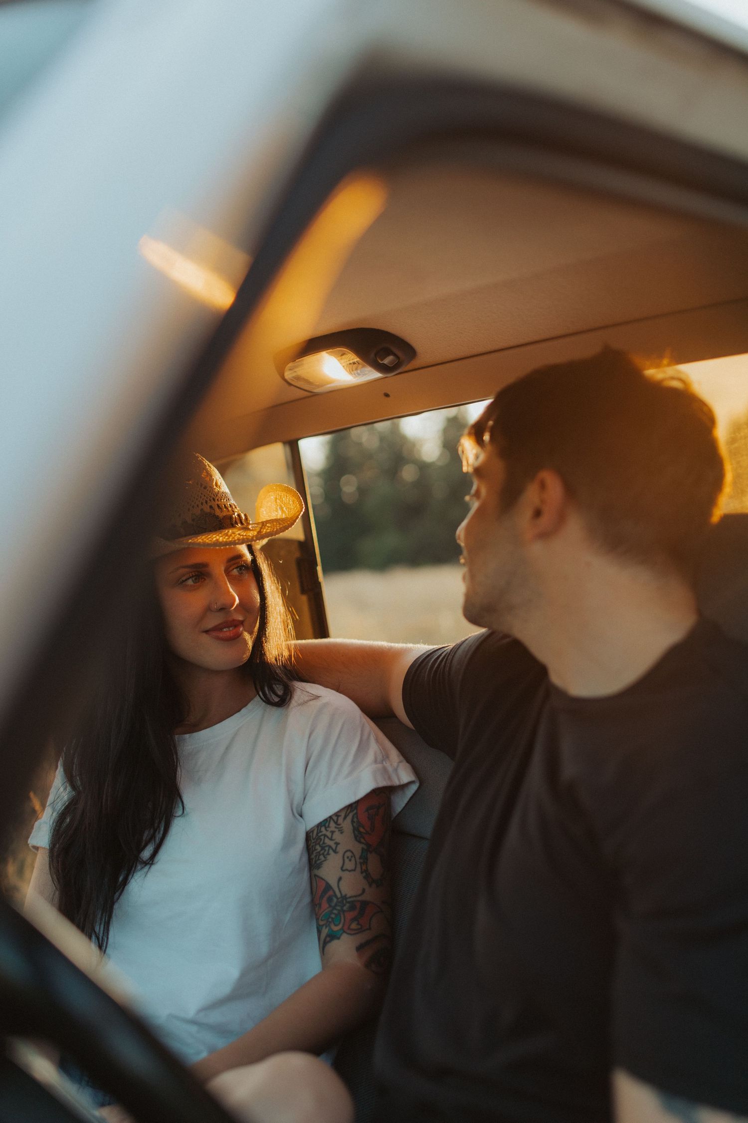 A couple shares a romantic moment inside a vintage van during golden hour sunset.