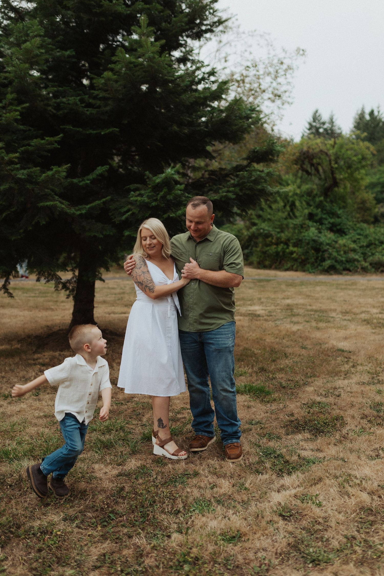Happy family with young toddler son enjoying a sunny day together in a grassy park setting.