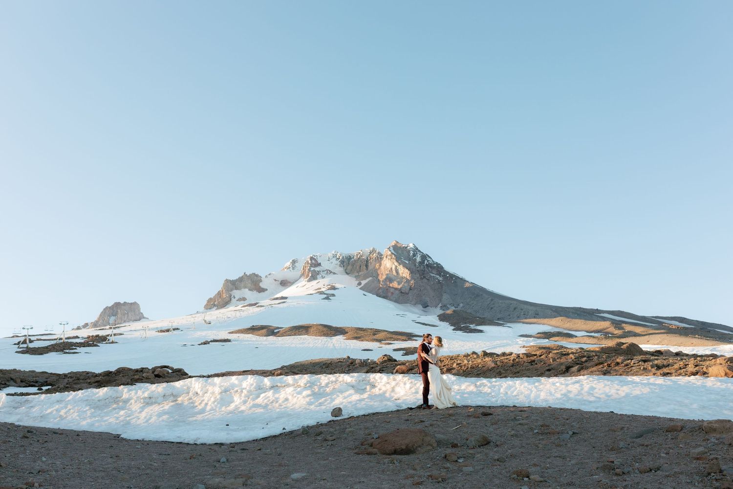Couple shares a quiet moment on a snowy landscape with a majestic mountain backdrop.
