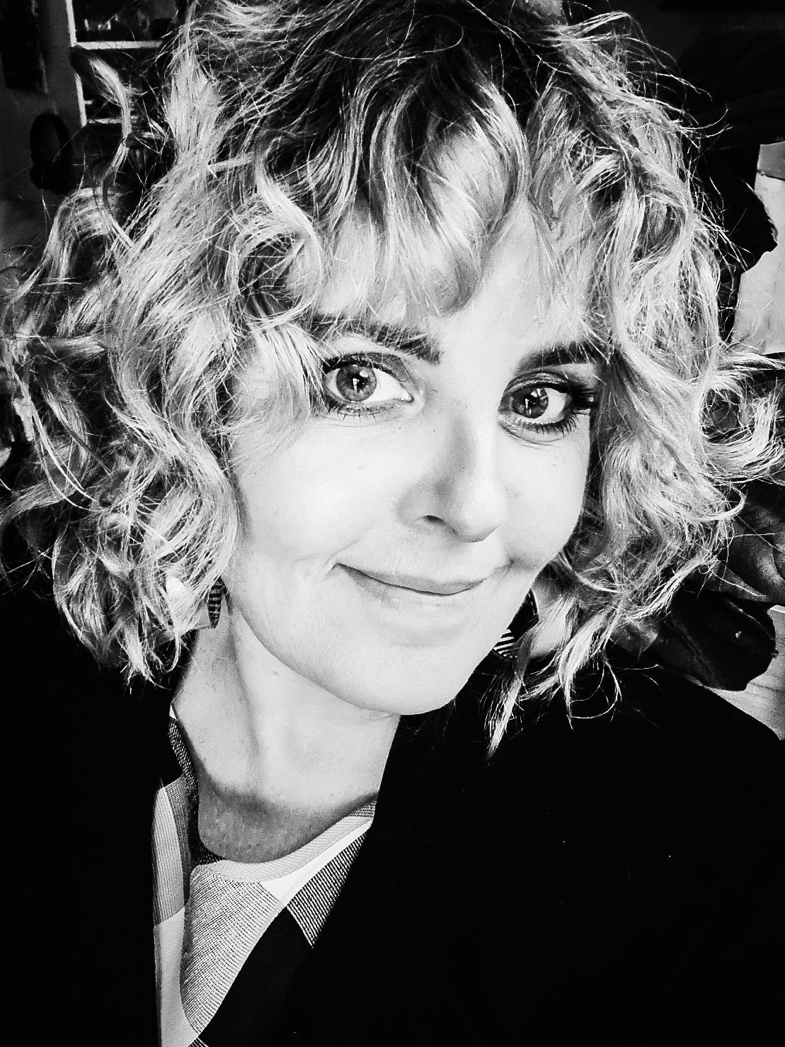 Black and white portrait of a woman with curly blonde hair smiling softly at the camera.