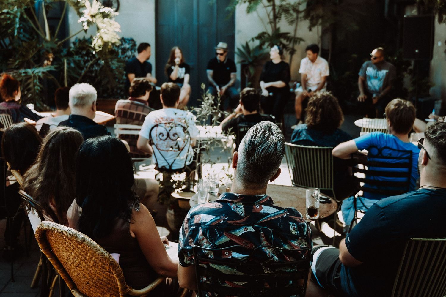 Diverse group of people seated outdoors at an intimate garden panel discussion event.