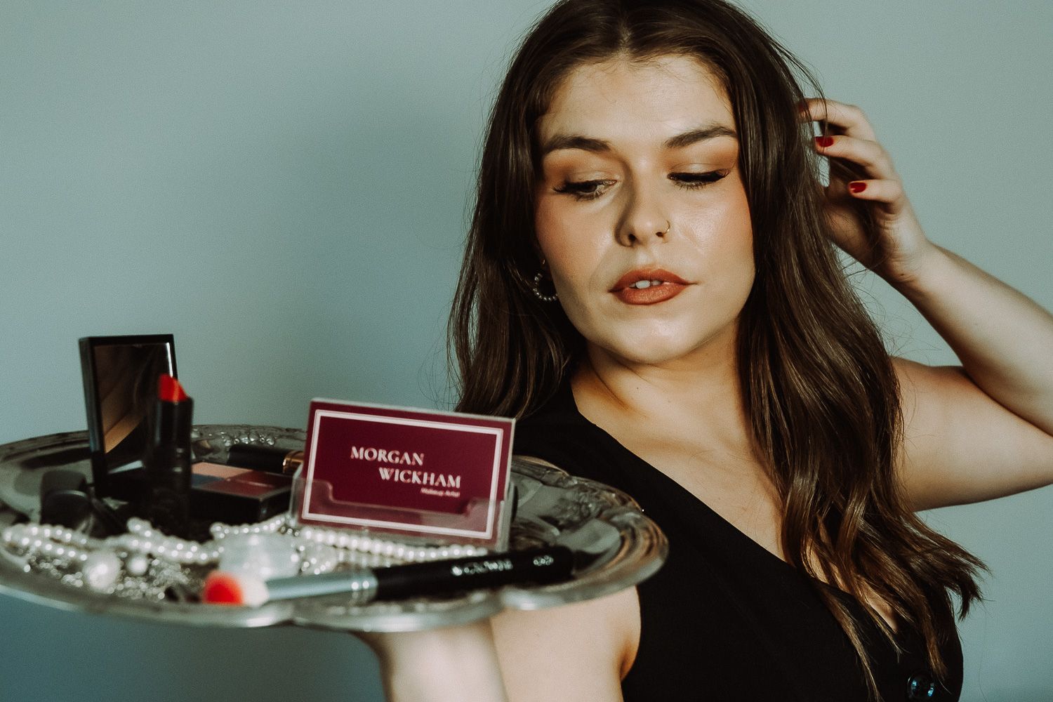 Young woman holding a silver tray with Morgan Wickham makeup products and cosmetics.