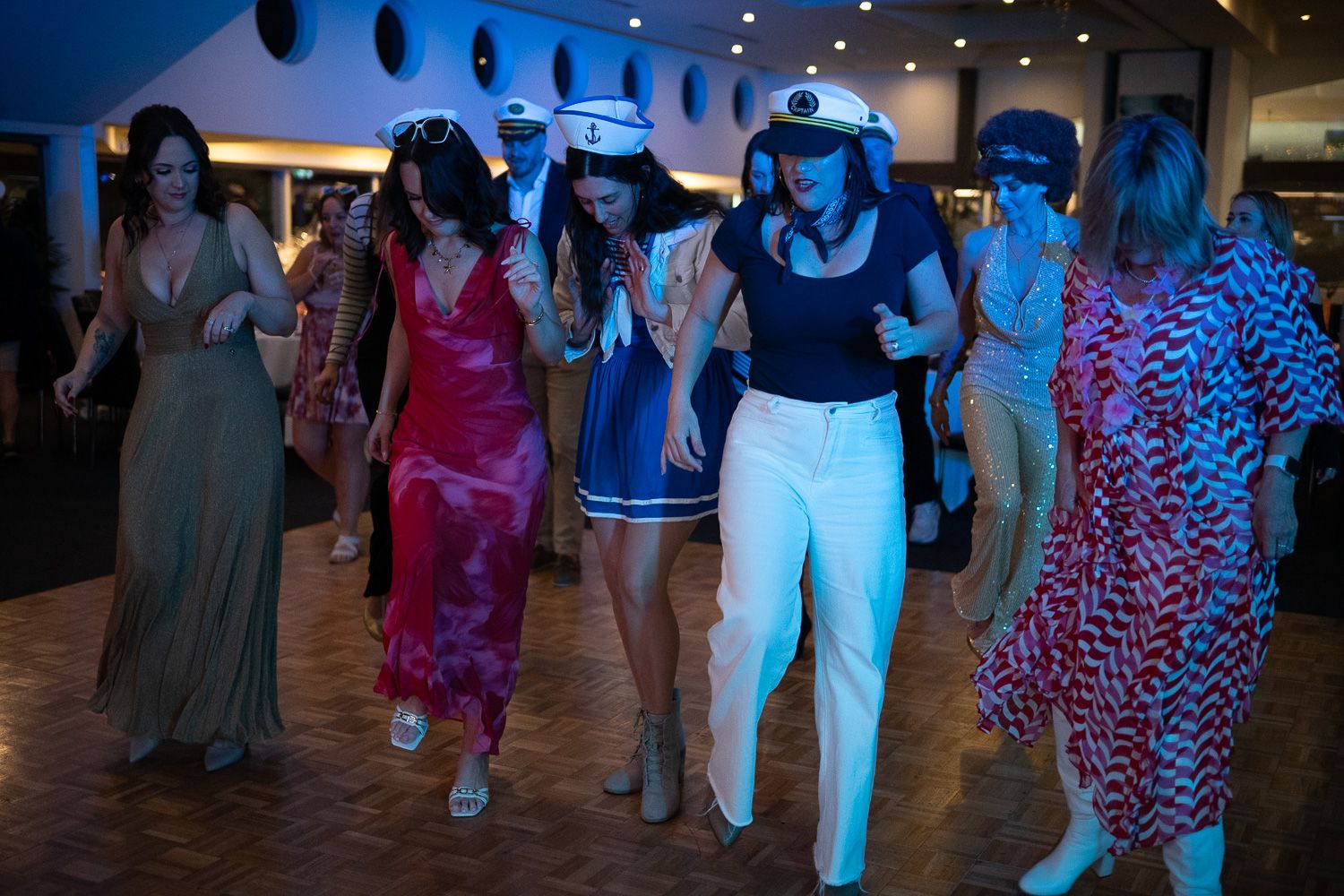 Group of women in costumes dancing together at a festive nautical themed party event.