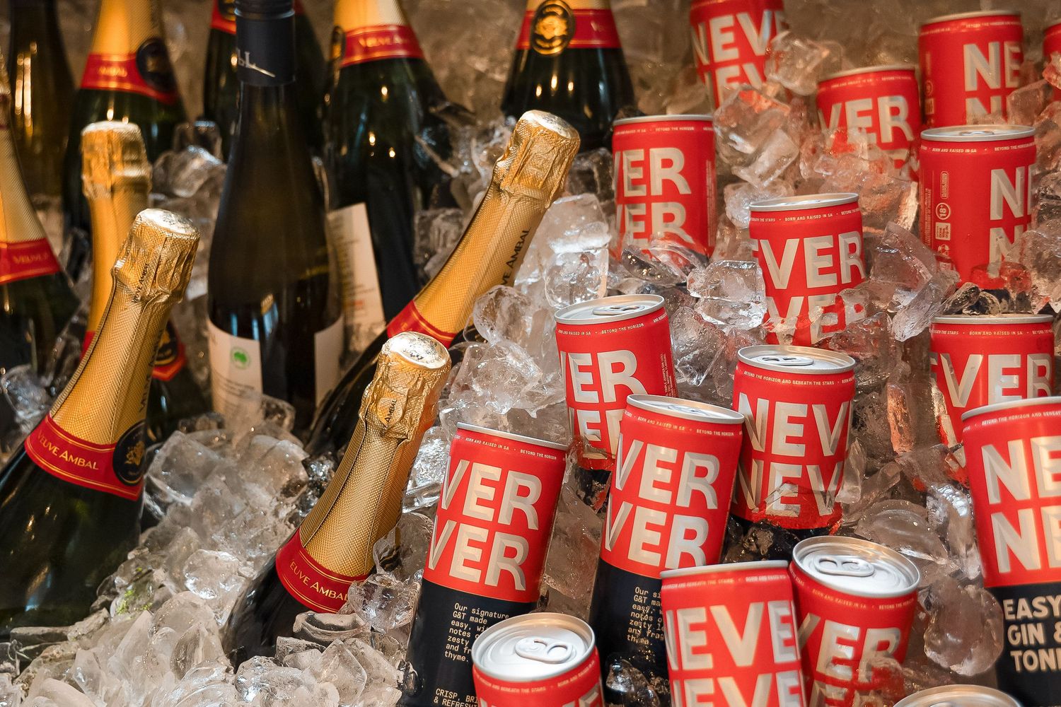 Champagne bottles and Never Never Gin cans chilling on ice at a party event.