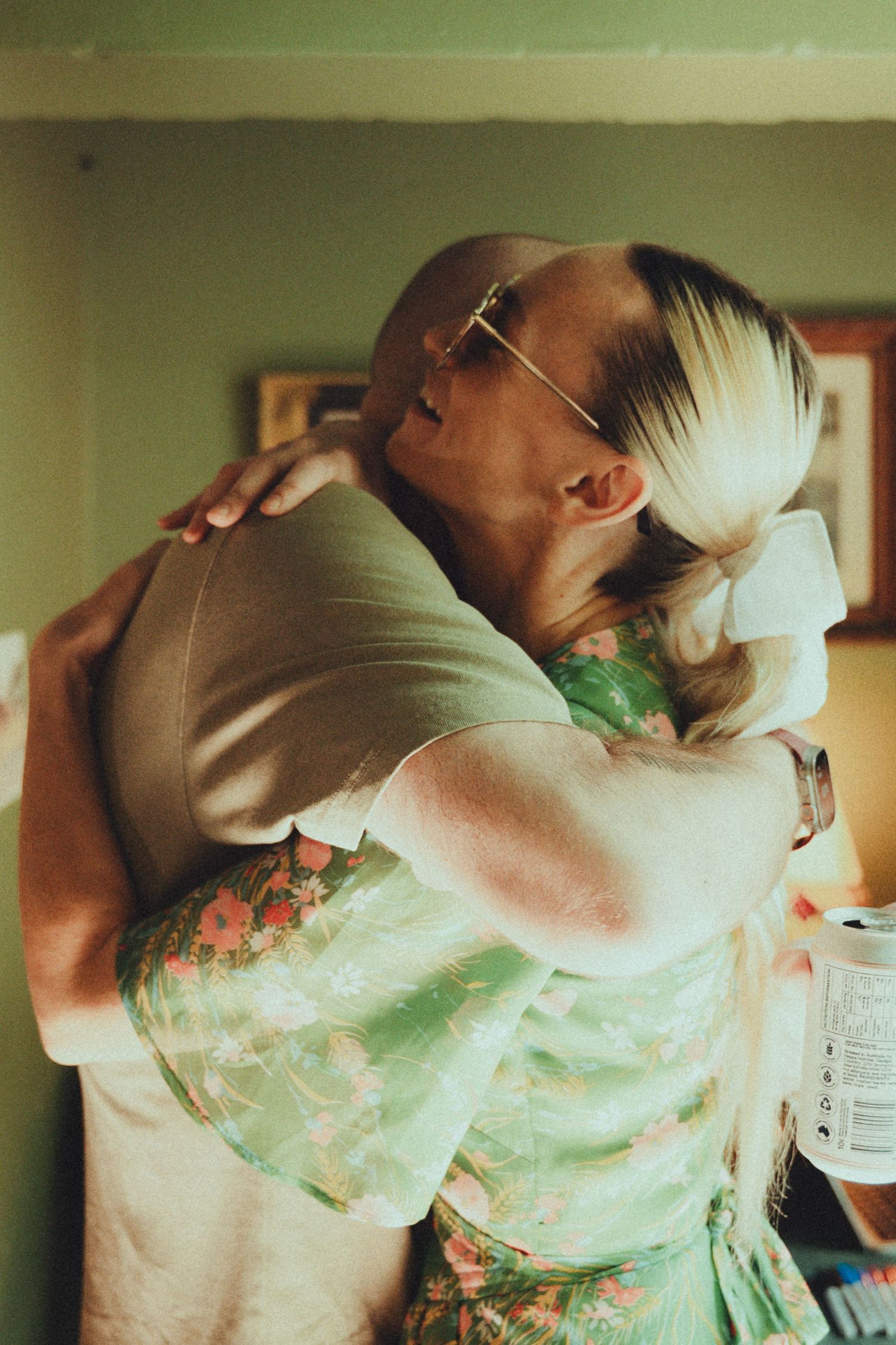 Two people sharing a warm embrace indoors in soft natural sunlight.